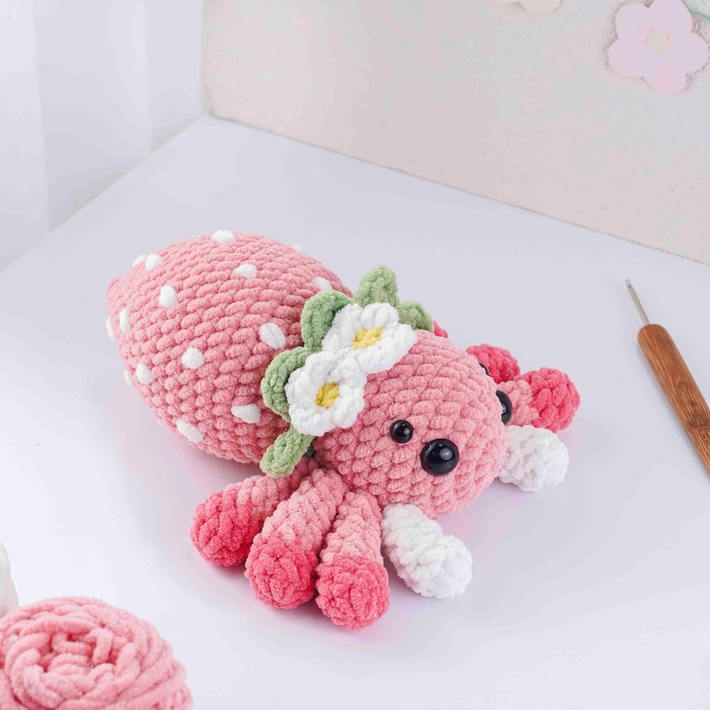 May include: A handmade pink crochet octopus with white polka dots, black eyes, and a floral headband. The octopus has eight tentacles with white tips and is a soft, plush toy.