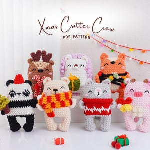 Op de afbeelding: Een verzameling handgemaakte gehaakte kerstbeestjes, waaronder een panda, een beer, een kat, een vos, een varken, een rendier en een konijn. Elk beestje is uniek ontworpen met feestelijke accessoires en kleuren. De tekst "Xmas Critter Crew PDF Pattern" is zichtbaar.