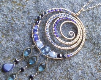 Golden swirl medallion necklace in light and dark blue with lapis lazuli, sapphires, crystals, and vintage blue dangles