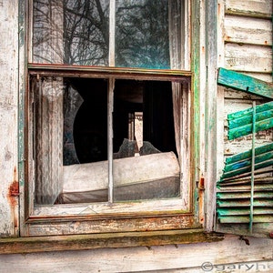 May include: A weathered wooden window with broken glass panes and a set of teal green shutters. The window is partially open and the shutters are hanging loosely.