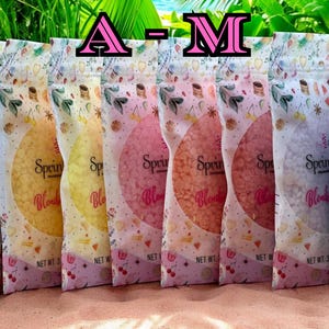 May include: A row of colorful bags of Sprinkles Blend fragrance beads. The bags are clear with a floral and cherry design. The beads inside are various shades of pink, yellow, and white. The text "Sprinkles Blend" is visible on the bags.