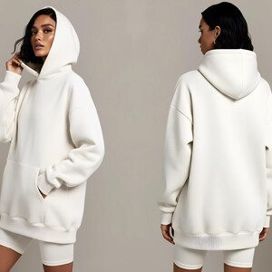 May include: Off-white hoodie with a front pocket and a matching pair of shorts. The hoodie has a drawstring hood and ribbed cuffs and hem. The model is wearing the hoodie and shorts. The outfit is made of a soft, comfortable material.