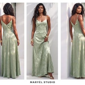 May include: A light green, floor-length dress with spaghetti straps and a V-neck. The dress has a subtle floral pattern and a flowing skirt. The model is wearing gold bracelets and heels. The text "MARY&Egrave;L STUDIO" is at the bottom.
