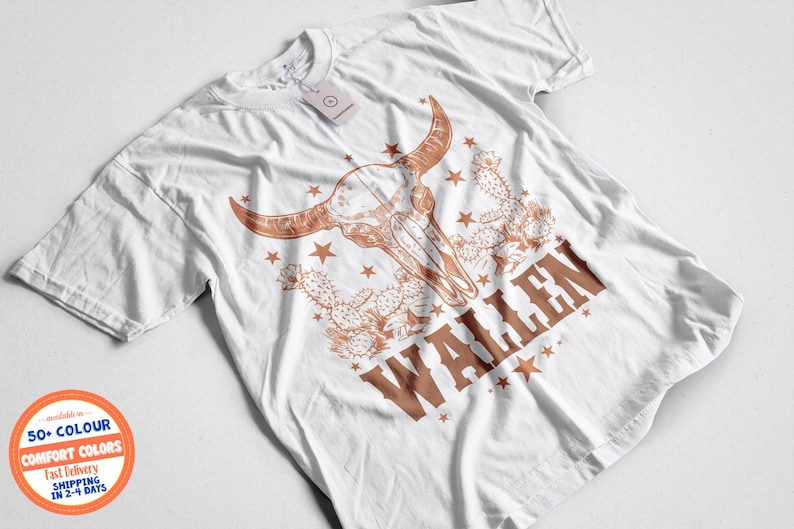 Pu&ograve; includere: T-shirt bianca con grafica di teschio di toro marrone, stelle e cactus. La parola "WALLEN" &egrave; stampata in marrone. Un'etichetta &egrave; attaccata alla maglietta.