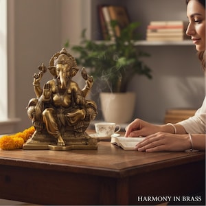 Woman reading beside a brass Ganesha statue on wooden table — meditation and wellness decor idea