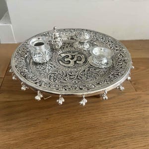 Macro shot of hand-engraved detailing on an antique German silver-plated brass pooja set showing the premium artisan finish.