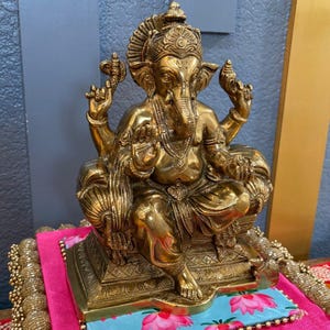 Brass Ganesha statue on colorful fabric background — Indian festival and gifting display