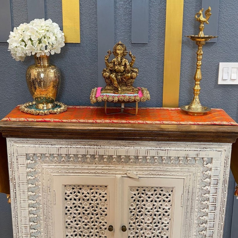 Handcrafted Brass Ganesha statue styled on wooden cabinet with lamps and flowers — Indian home temple decor