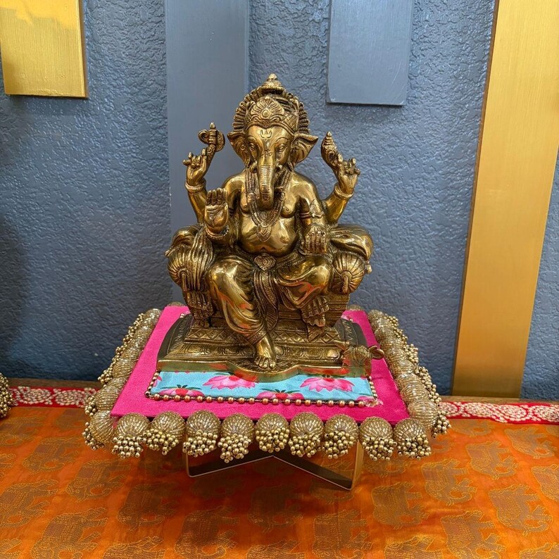Decorative platform display of gold Ganesh idol with blue wall background — entrance foyer decor