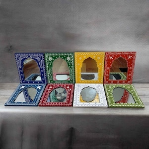 May include: Eight decorative mirrors with ornate frames in various colors, including blue, green, yellow, red, and white. Each mirror has a unique design with intricate details and a small arched opening.