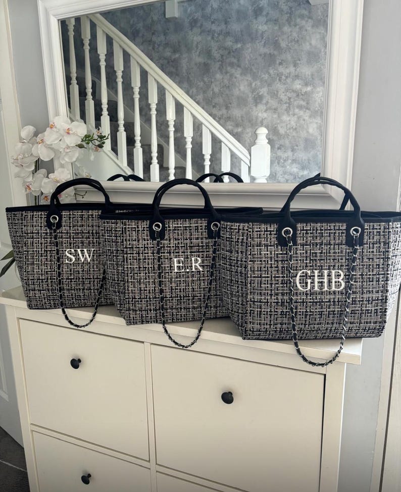 May include: Three black and white tweed tote bags with black chain straps and white monogram initials. The initials are "SW", "ER", and "GHB".