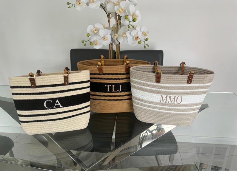 May include: Three striped rope tote bags with leather handles. The bags are personalized with the initials "CA", "TLJ", and "MMO".