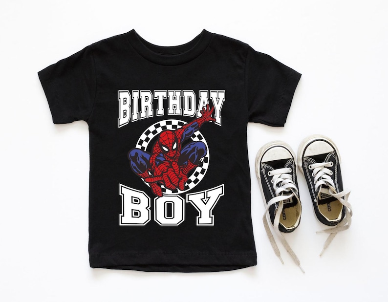 A black t-shirt with a Spider-Man graphic and the text "BIRTHDAY BOY" printed on it, along with a pair of black and white sneakers.