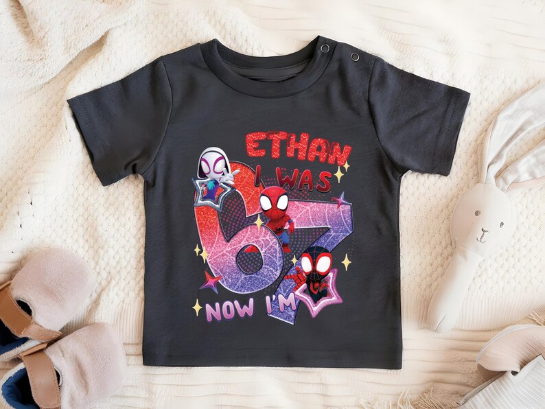 A black t-shirt with a graphic design featuring Spider-Man characters and the text "ETHAN WAS 6 NOW I'M" printed on it.