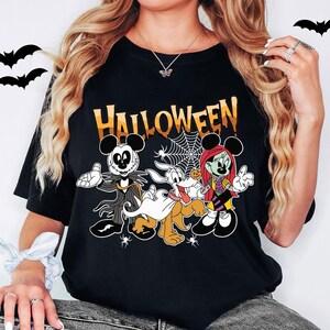 A woman wearing a black t-shirt with a Halloween-themed graphic design featuring characters from the Disney movie " jack Skellington and the Ghostly Dog".