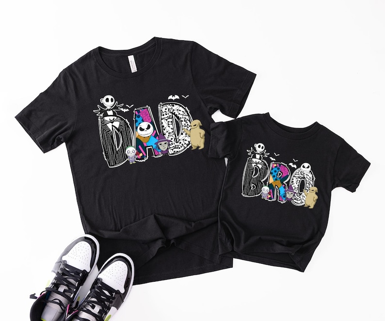 A black t-shirt with a Halloween-themed design and a smaller t-shirt underneath it, along with a pair of sneakers.