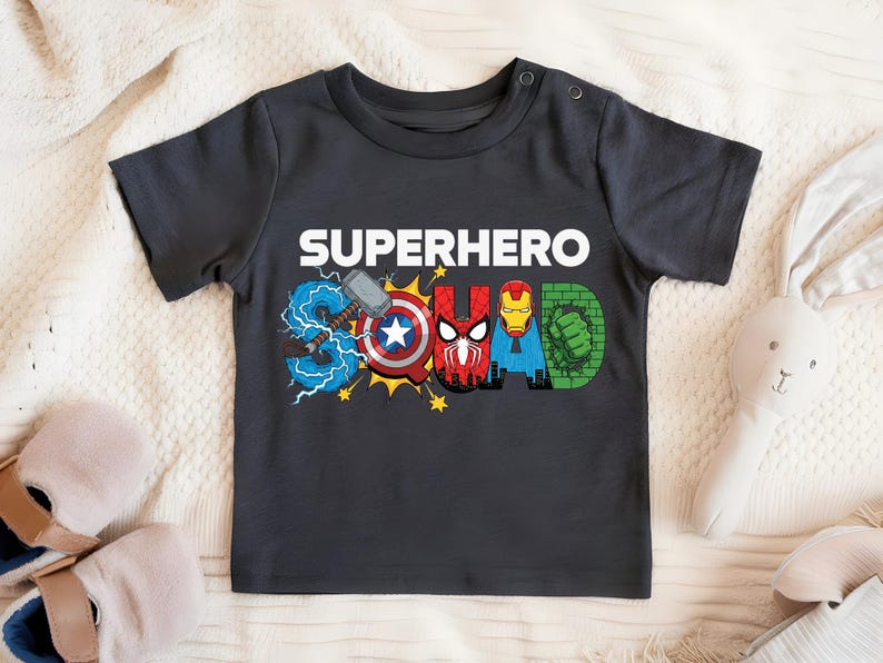 A black t-shirt with the text "SUPERHERO SQUAD" printed on it, featuring various superhero logos and symbols.