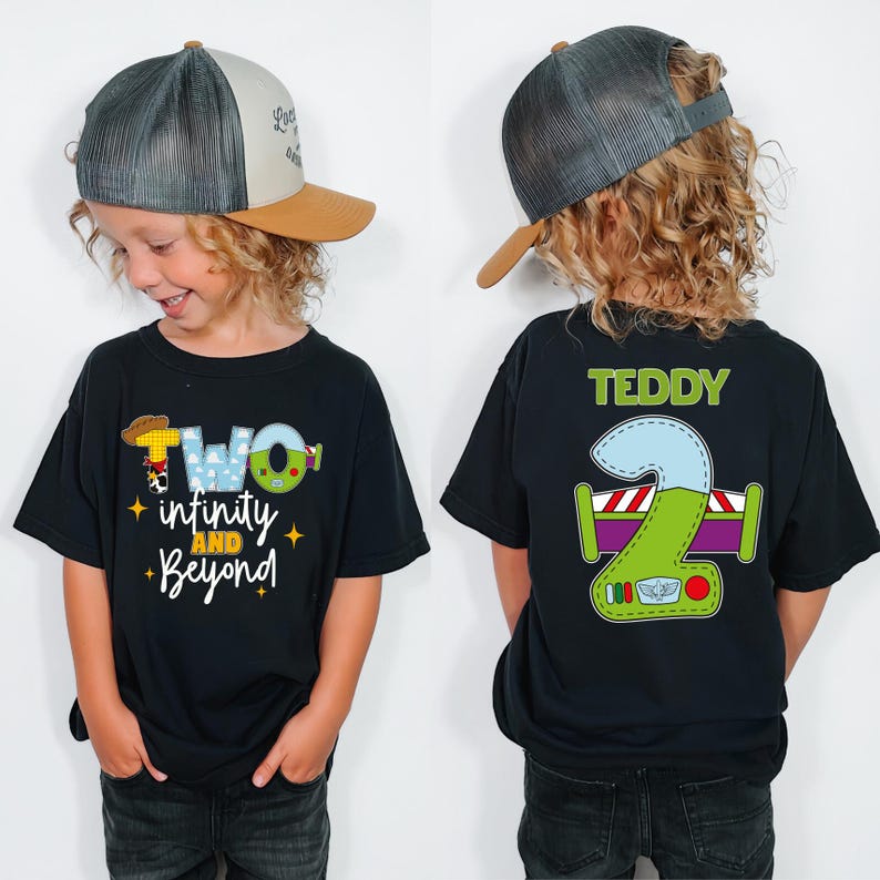 A young boy wearing a black t-shirt with a cartoon character and text, and a baseball cap, smiling at the camera.