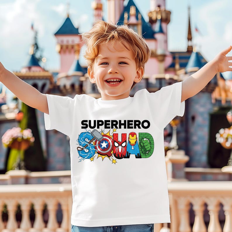 A young boy wearing a white t-shirt with the text "SUPERHERO SQUAD" printed on it, smiling and having his arms outstretched in front of a colorful, castle-like structure.