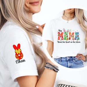 A woman wearing a white t-shirt with a colorful Easter bunny design and the text "This MAMA wears her heart on her sleeve" printed on it.