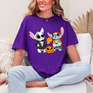a woman sitting on a couch wearing a purple shirt with cartoon characters on it
