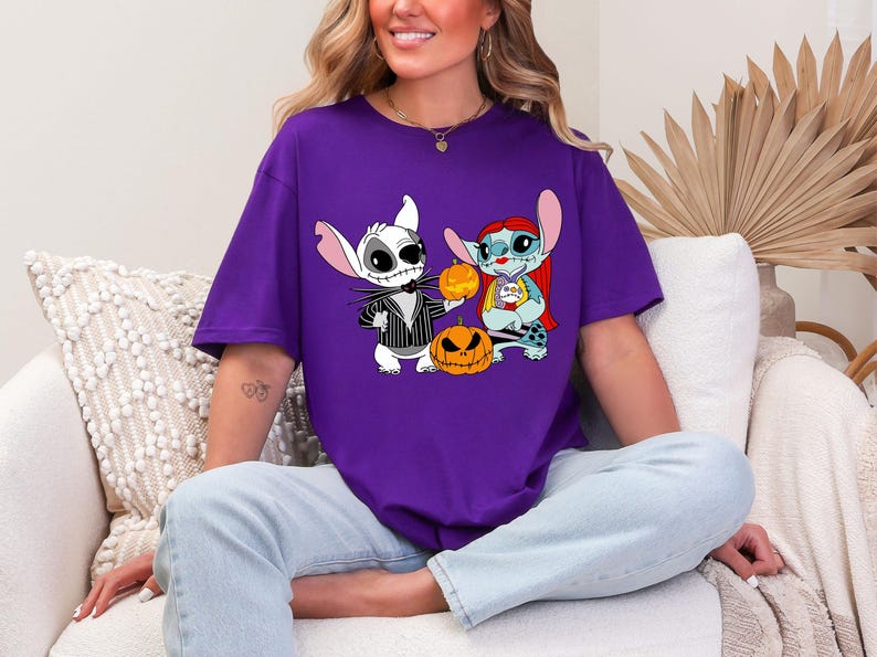 a woman sitting on a couch wearing a purple shirt with cartoon characters on it