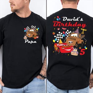 A black t-shirt with a personalized design featuring a cartoon character and birthday-themed elements.