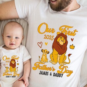 May include: White t-shirt and baby onesie set with a Lion King theme. The design includes the text "Our First 2025" and "Father's Day" with lion illustrations, hearts, and a crown. The names "JAMES & DADDY" are also included.