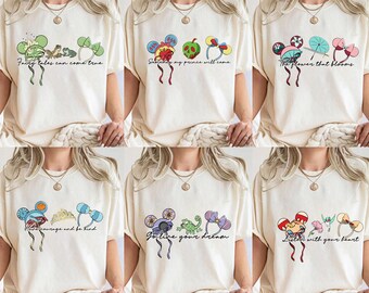Peut inclure: T-shirts crème avec divers motifs graphiques. L'un présente un motif de grenouille et de trèfle avec le texte "Fairy tales can come true". Un autre a un motif d'oreille de Mickey Mouse avec le texte "Somebody my prince will come."