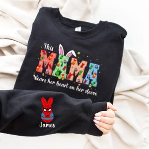 A black t-shirt with a colorful design and text, and a person's arm with a Spiderman character on it.
