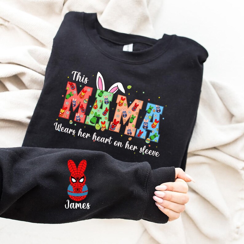 A black t-shirt with a colorful design and text, and a person's arm with a Spiderman character on it.