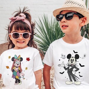 A young girl and a young boy are standing together, both wearing white t-shirts with cartoon characters and designs.