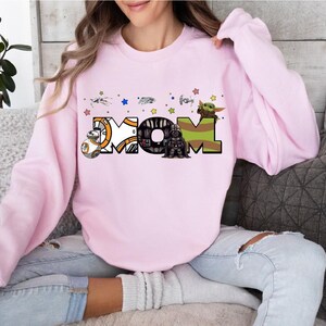 A woman wearing a pink sweatshirt with a graphic design on it.