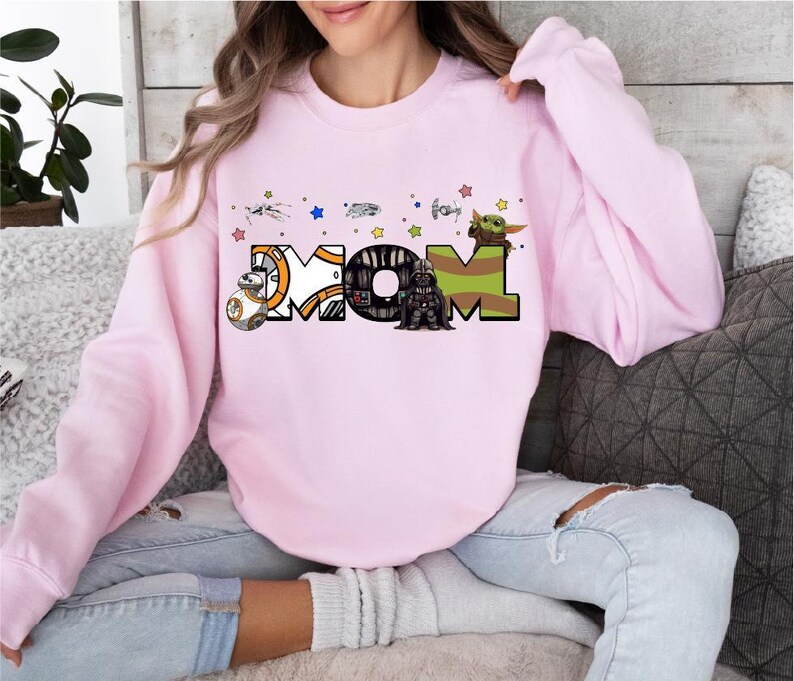 A woman wearing a pink sweatshirt with a graphic design on it.