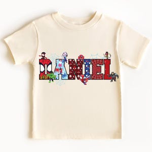 A white t-shirt with the name "DAMNEL" printed on it, made up of various cartoon character images.