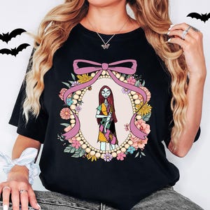 A woman wearing a black t-shirt with a graphic design featuring a character from the movie "Sneaky Nancy".