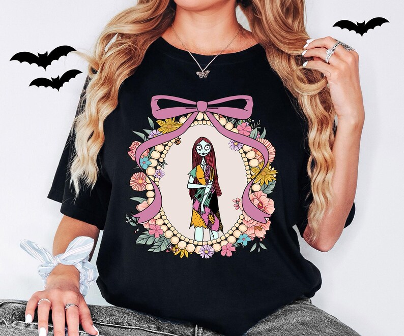 A woman wearing a black t-shirt with a graphic design featuring a character from the movie "Sneaky Nancy".