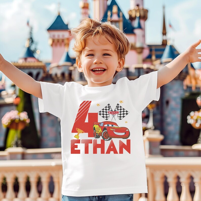 A young boy wearing a white t-shirt with a red and black design featuring a race car and the number 4, along with the text "Ethan".