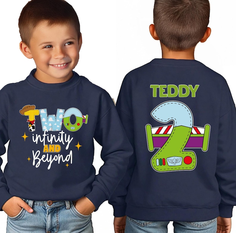 A young boy wearing a navy blue sweatshirt with a cartoon character and text printed on it.