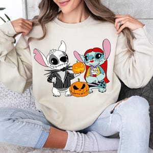 a woman sitting on a couch wearing a sweatshirt with cartoon characters on it