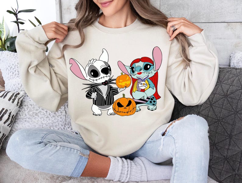 a woman sitting on a couch wearing a sweatshirt with cartoon characters on it