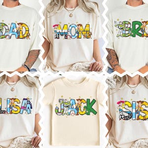 May include: Cream-colored t-shirts with the words "DAD", "MOM", "BRO", "LISA", "JACK", and "SIS" in colorful, cartoon-style lettering. Each word features characters from a popular animated movie.