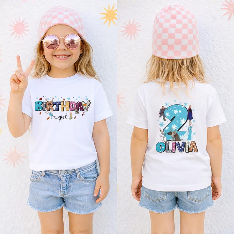 A young girl wearing a white t-shirt with a birthday message and a pink beanie is smiling and making a peace sign.