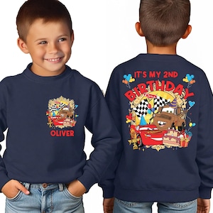 A young boy wearing a blue sweatshirt with a personalized design featuring a character from the Cars movie franchise.