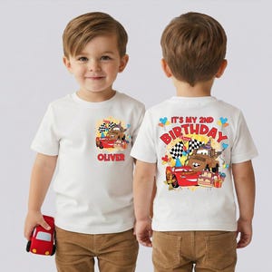 A young boy wearing a white t-shirt with a Cars-themed design and text on the back.
