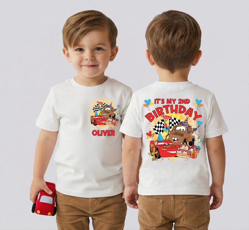 A young boy wearing a white t-shirt with a Cars-themed design and text on the back.