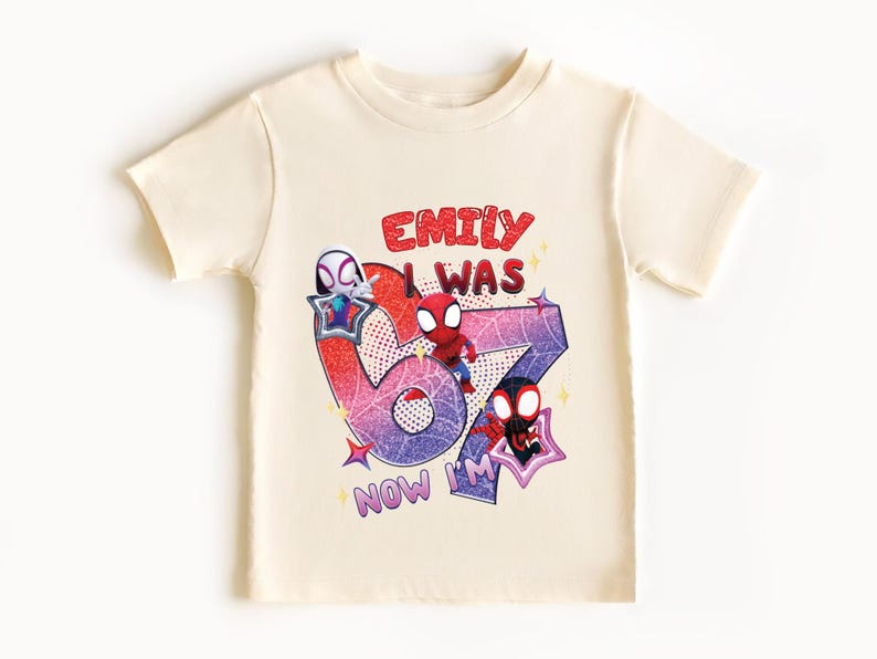 A white t-shirt with a graphic design featuring a Spider-Man character and text that says "Emilly was 67 now I'm".