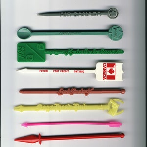 Peut inclure: Une collection de bâtonnets à cocktail vintage de différentes couleurs, dont le vert, le rouge et le jaune. Certains bâtonnets portent des inscriptions telles que "AIR CANADA" et "Monte Carlo Casino". Les bâtonnets ont des formes et des motifs variés.