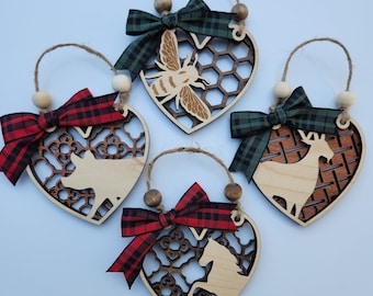 May include: Four wooden heart-shaped ornaments with different animal silhouettes and patterned backgrounds. Each ornament has a red and black checked bow and a brown wooden bead string.