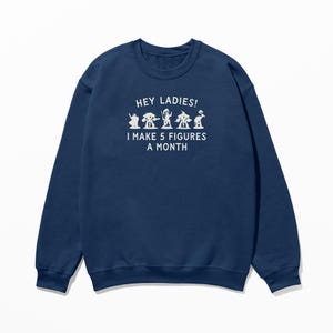May include: Navy blue sweatshirt with white text that reads "Hey Ladies! I make 5 figures a month". The text is accompanied by a row of five small white figures.
